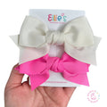 Two hair bows, one white and one pink, on a card with 'Ellie's Premier Bows' branding.