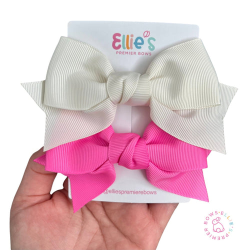 Two hair bows, one white and one pink, on a card with 'Ellie's Premier Bows' branding.